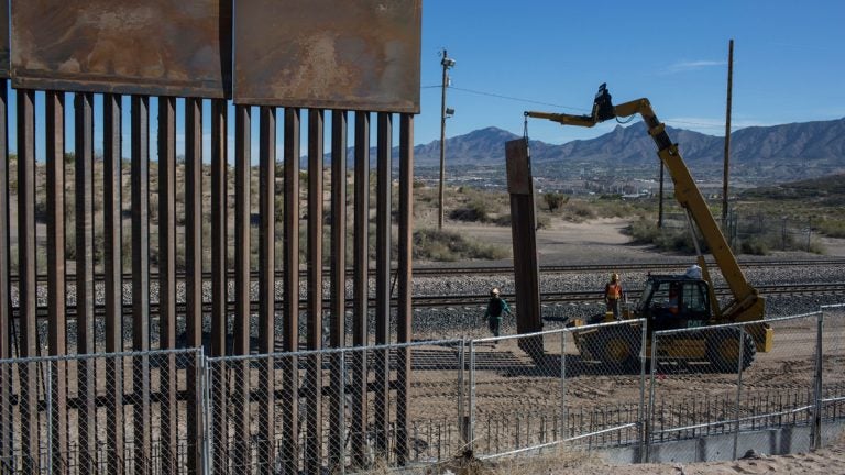 In this March 30, 2017 file photo, Workers use a crane to lift a segment of a new fence into place on the U.S. side of the border with Mexico. (AP Photo/Rodrigo Abd)