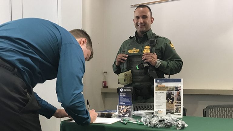 Border Patrol Agent Lanllony Molina of Erie, Pennsylvania, smiles as a job-seeker gives his information during an employment fair Thursday at Temple University. (Laura Benshoff/WHYY)