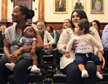 Nine-month-old Aarav Vyas (right) wears a shirt with the slogan ''I sleep with this side up.'' He and his mother, Aasta Mehta, along with Jasmine Pitt-Mitchell and her 6-month-daughter, Leilani (left) helped to kick off Philadelphia's safe sleeping campaign. (Emma Lee/WHYY)