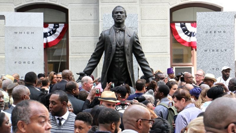 A statue of Octavius Catto at it's unveilling - statue facing front with arms spread open and back, people in the foreground in Philadelphia