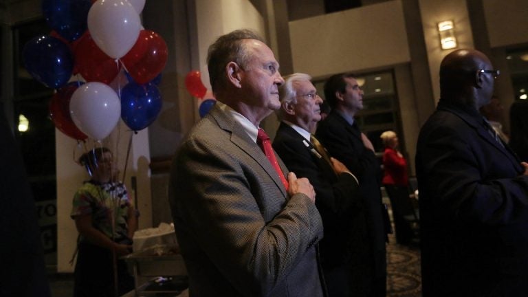 Former Alabama Chief Justice and U.S. Senate candidate Roy Moore, stops to say the Pledge of Allegiance as he walks around greeting supporters before his election party, Tuesday, Sept. 26, 2017, in Montgomery, Ala. (AP Photo/Brynn Anderson)