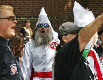  Members of the KKK are escorted by police past a large group of protesters during a KKK rally Saturday, July 8, 2017, in Charlottesville, Va. A month later, as white supremacists protested the proposed removal of a Confederate monument, counter-protester Heather Heyer was killed when James Alex Fields drove a speeding car into the crowd. (AP Photo/Steve Helber) 