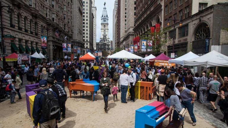 People and vendors tents set upon beach sand on Broad Street with City Hall in the background