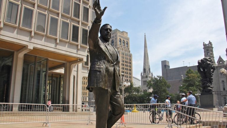 Police stand guard at the Frank Rizzo statue on the grounds of the Municipal Services Building. (Emma Lee/WHYY, file)