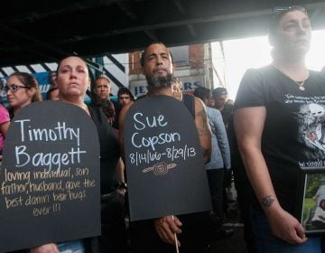 People hold signs and photos of friends and loved ones lost to opioid overdoses under the El Thursday for the March in Black that traveled from the York-Dauphin Station to Somerset Station. (Brad Larrison for NewsWorks)