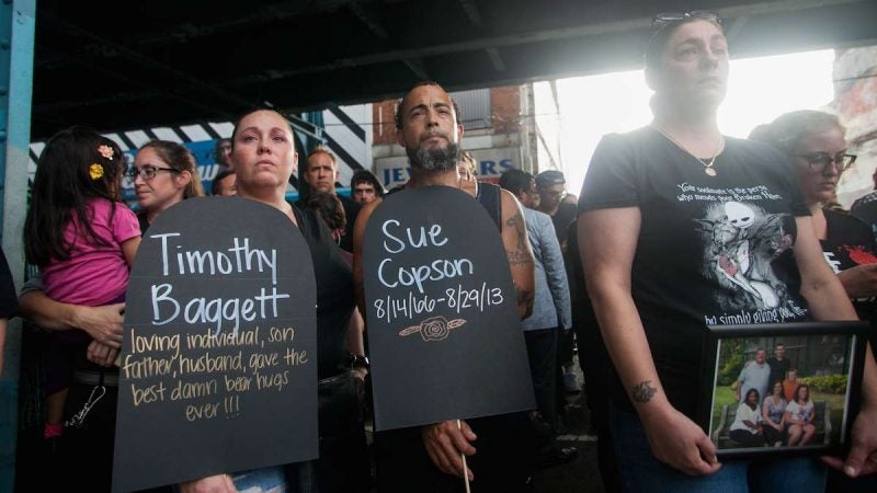 People hold signs and photos of friends and loved ones lost to opioid overdoses under the El Thursday for the March in Black that traveled from the York-Dauphin Station to Somerset Station. (Brad Larrison for NewsWorks)