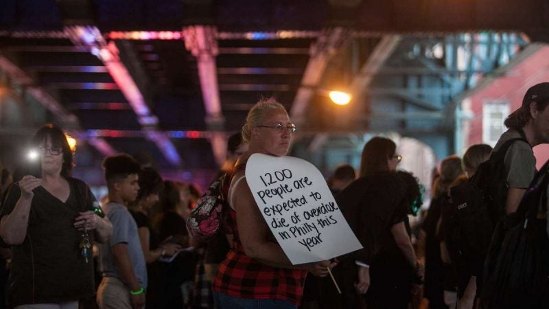 Teresa Force of Lawncrest holds a sign and listens to speakers under The El during the March in Black Thursday evening. (Brad Larrison for NewsWorks)