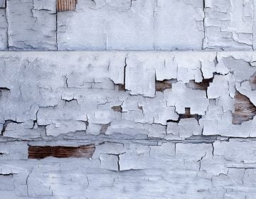 Distressed building wall with white aged paint chipping off
