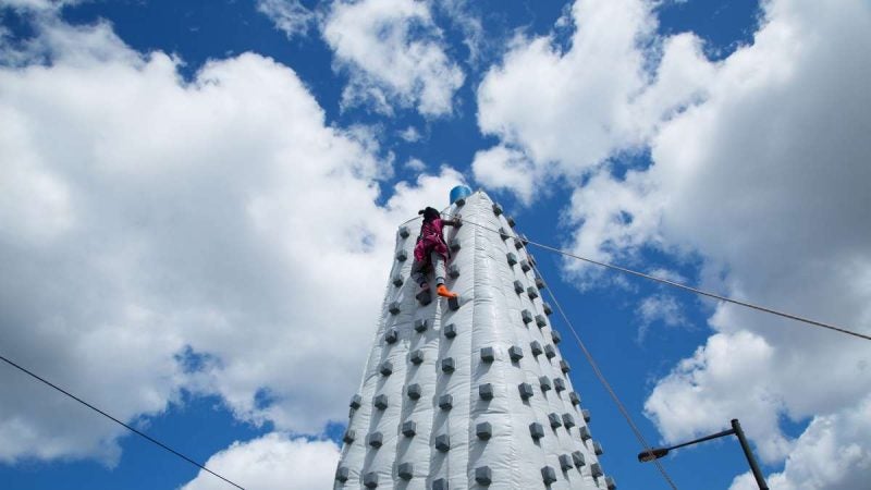 A girl approaches the top of an inflatable rock-climbing wall on Woodland Avenue. (Annie Risemberg for NewsWorks)