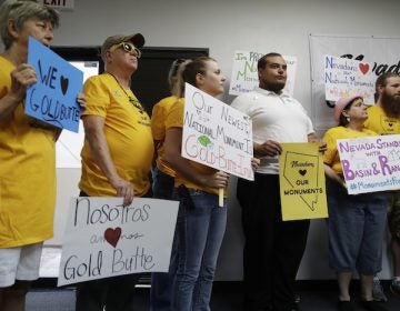 People hold up signs during a news conference by supporters of the Basin and Range and Gold Butte National Monuments, Monday, July 31, 2017, in Las Vegas. The supporters held the news conference after Interior Secretary Ryan Zinke cancelled a meeting with Gold Butte advocates scheduled for Monday. (AP Photo/John Locher)
