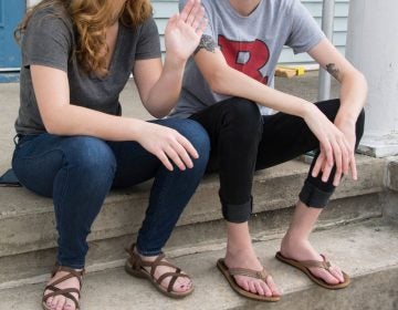 Two students sit on the front porch at one of the three 