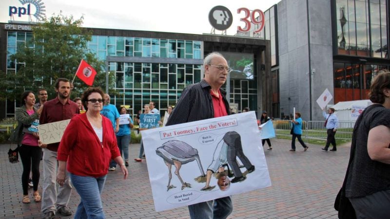 Protesters parade outside PBS 39 studios in Bethlehem where U.S. Sen. Pat Toomey held a televised town hall. Toomey has been criticized for being unavailable to constituents since the presidential election. (Emma Lee/WHYY)