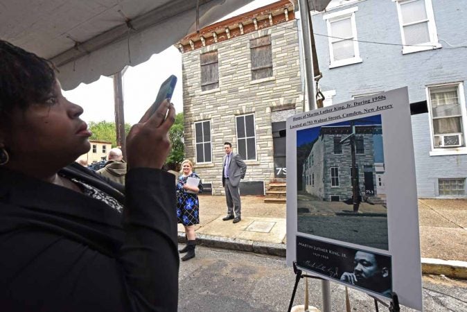 At the September 2016 press conference to announce the preservation of the house at 753 Walnut Street where Martin Luther King, Jr. stayed, a woman photographs a poster; the house is in the background.  (April Saul/for WHYY)