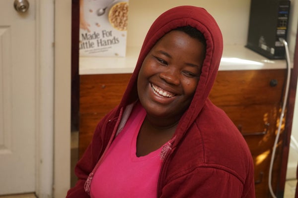 A smiling Tatiana Angama in a pink shirt and maroon hoodie