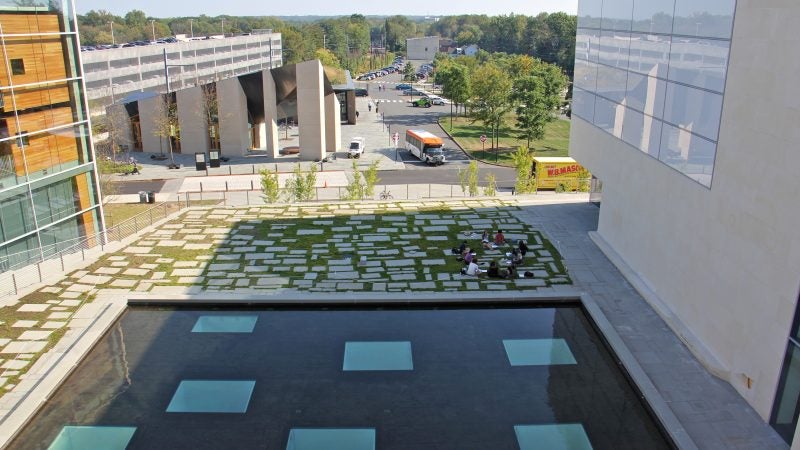 Students meet on the grass beside the reflecting pool that sits above The Forum in the Lewis Center for the Arts Complex. (Emma Lee/WHYY)