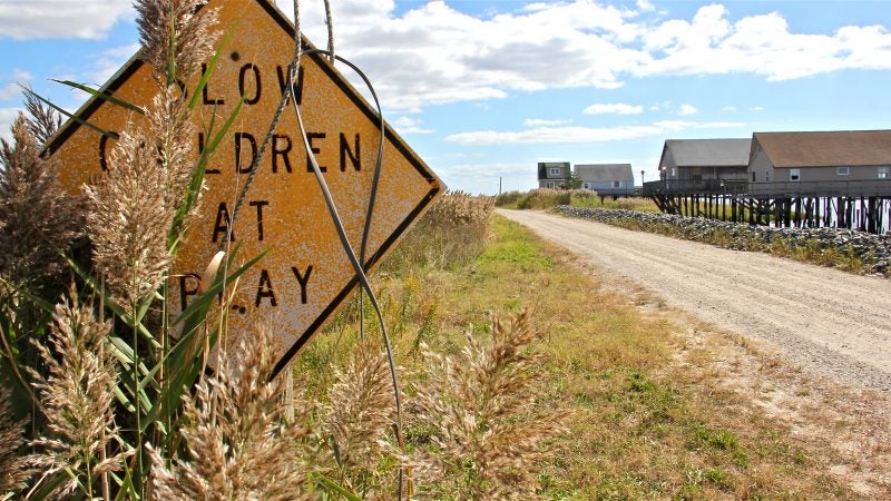An overgrown sign warns of children at play along the dirt road that leads to the deserted homes of Bay Point.