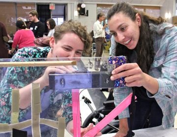 Rachel Adler (left) and Nicole Maximowicz take measurments before designing a wheelchair tray that will protect Ana's communication device