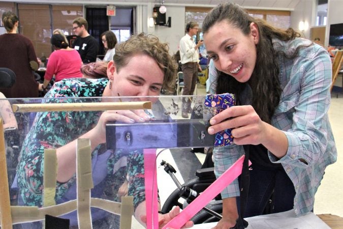 Rachel Adler (left) and Nicole Maximowicz take measurments before designing a wheelchair tray that will protect Ana's communication device