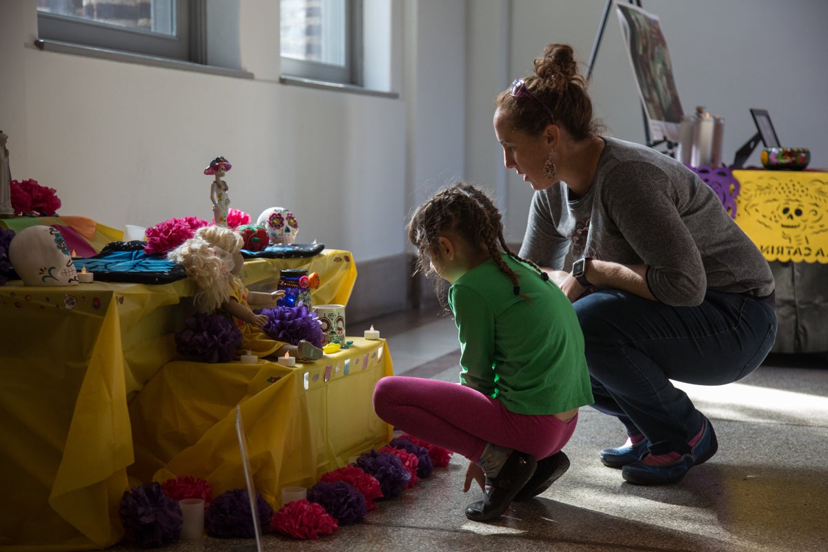 Amy Romaine and her daughter Eleanor, 7, check out the community altars at the Penn Museum's annual Day of the Dead celebration