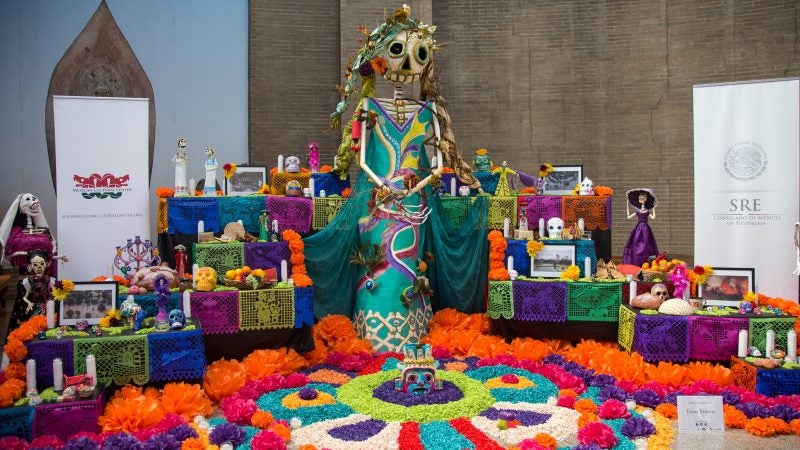 a day of the dead altar is decorated with skeletons, photos, candles and brightly colored paper flowers