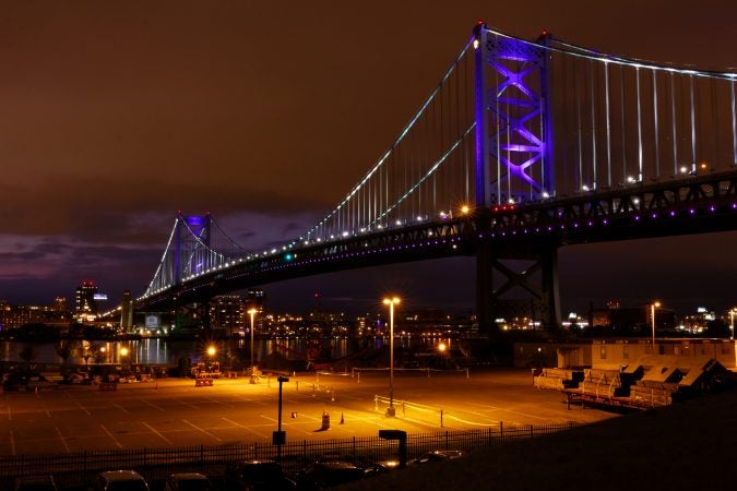 The ben Franklin Bridge is illuminated with purple lights to call attention to overdose victims during the Regional Candlelight Vigil at Camden Waterfront Stadium. (Bastiaan Slabbers for WHYY)