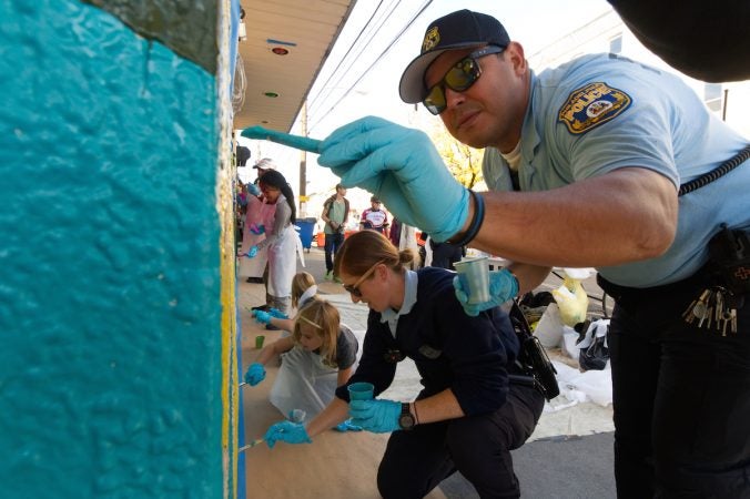 Police officers join kids as they take part in the creation of a mural during Philly Free Streets event, Saturday, Oct. 28, 2017. (Bastiaan Slabbers for WHYY)