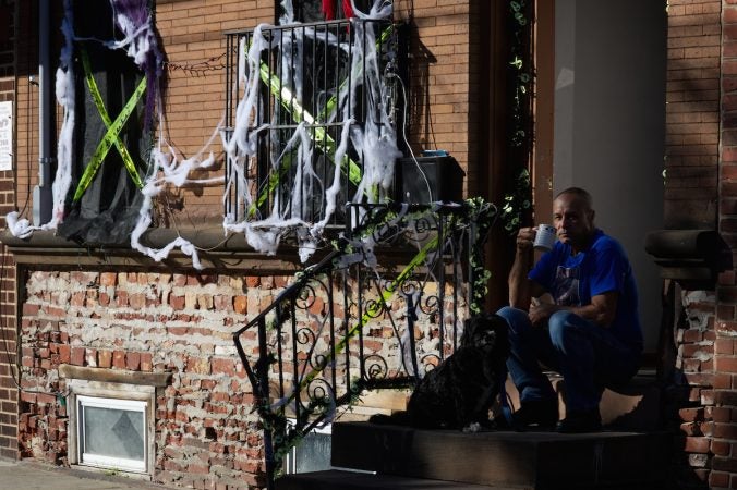 From his stoop a resident watches human-powered traffic go past during Philly Free Streets, Saturday, Oct. 28, 2017. (Bastiaan Slabbers for WHYY)