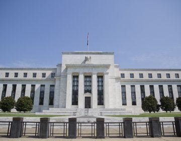 The Federal Reserve Building; white columns, black fencing against a blue sky