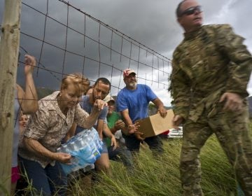 A member of the Puerto Rican National Guard delivers food and water brought via helicopter to victims of Hurricane Maria, to the  San Lorenzo neighborhood of Morovis, Puerto Rico, Saturday, Oct. 7, 2017. (AP Photo/Ramon Espinosa)