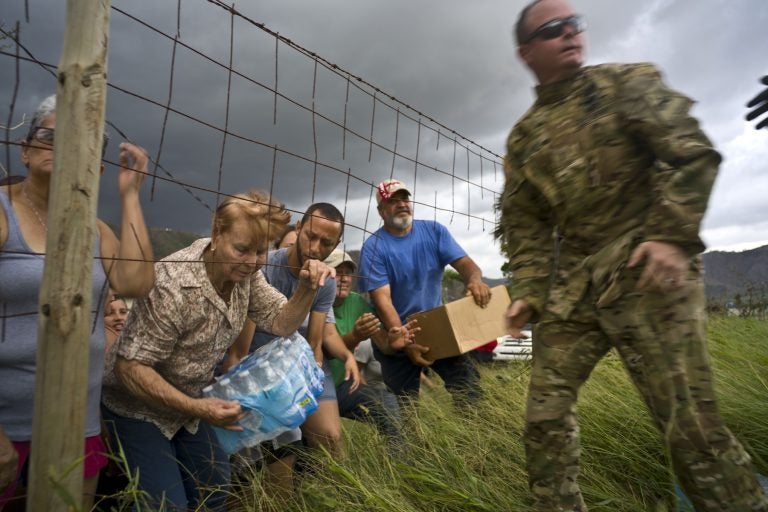 A member of the Puerto Rican National Guard delivers food and water brought via helicopter to victims of Hurricane Maria, to the  San Lorenzo neighborhood of Morovis, Puerto Rico, Saturday, Oct. 7, 2017. (AP Photo/Ramon Espinosa)