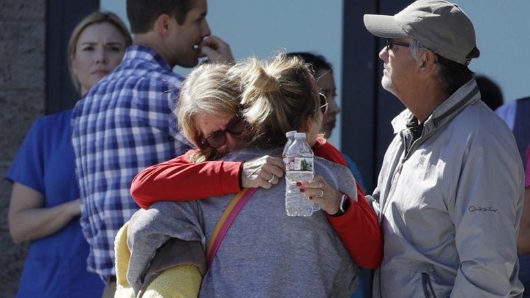 Two women embrace outside of a family assistance center