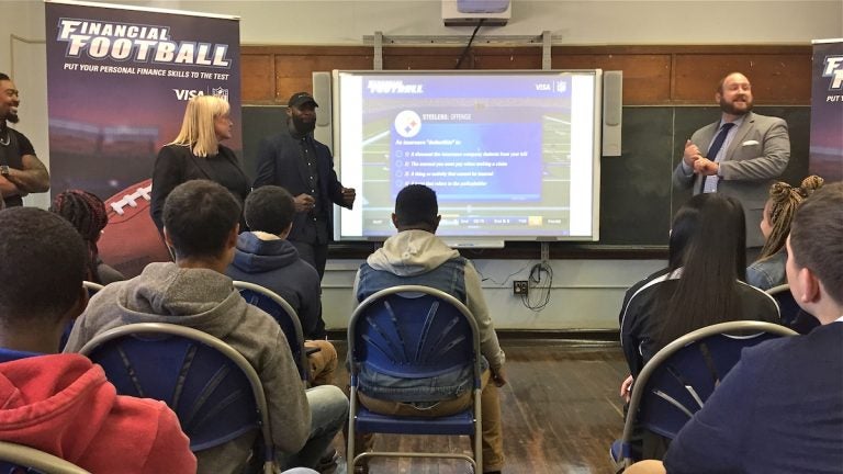 Eagles player Malcolm Jenkins (center left) speaks about financial literacy to students at Bodine High School in Philadelphia (Avi Wolfman-Arent/WHYY)