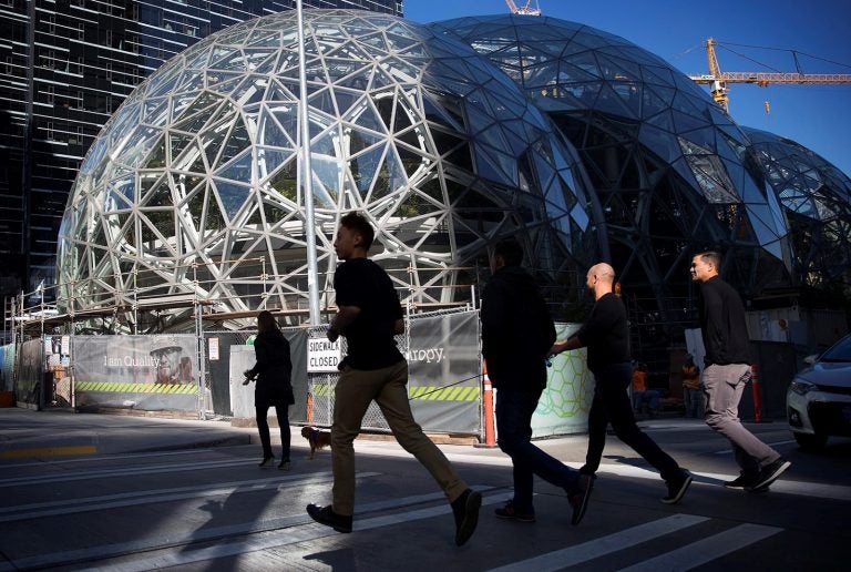 People in shaddow walk past a geometric building (Amazon's Seattle HQ)