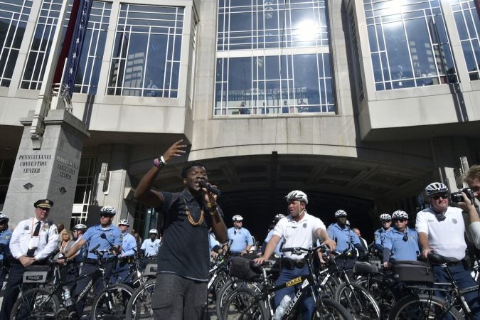 A man speaks in front of a line of officers outside of the convention center