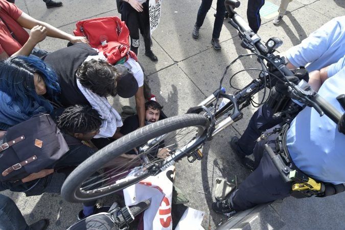 A man is seen on the ground, a group of people around him, a bicycle wheel