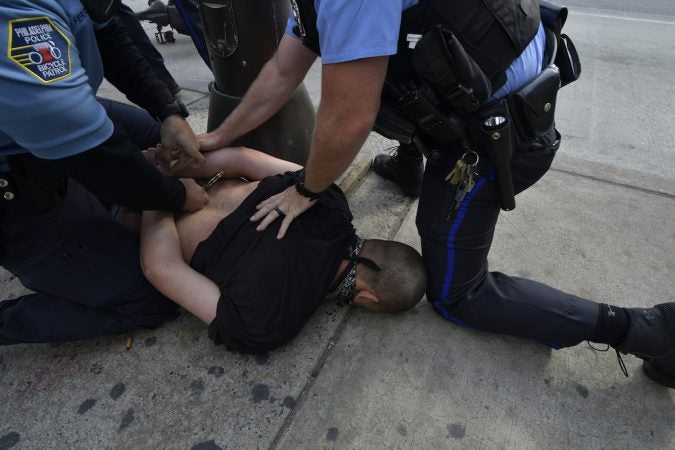 A protester is held on the ground, face down by an officer