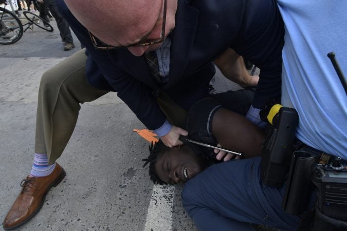 A protester is held on the ground, face down by an officer