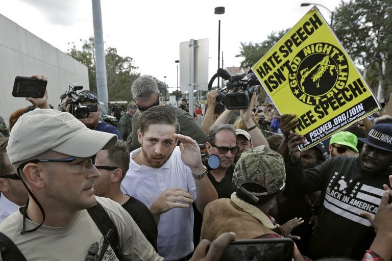 A supporter of white nationalist Richard Spencer (center in white shirt) tries to cover up as he clashes with the crowd after a speech by Spencer on Thursday at the University of Florida in Gainesville. A crowd of people clash with protesters