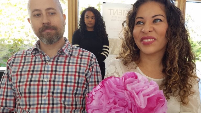 A man in flannel and a woman holding a pink bouquet of paper flowers