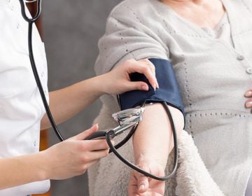 Nurse taking elderly woman's blood pressure in nursing home