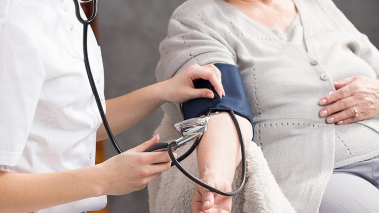 Nurse taking elderly woman's blood pressure in nursing home