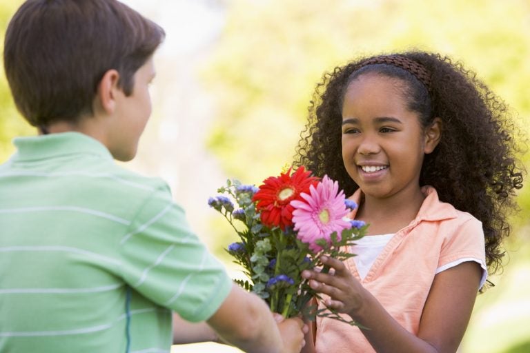 Young boy giving young girl flowers and smiling