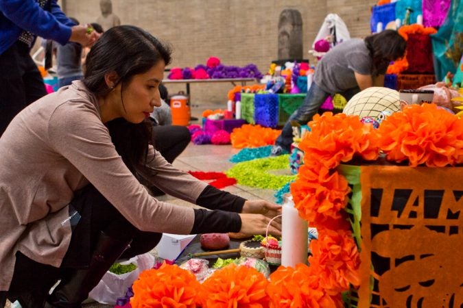 Virginia Rivera, with ether Mexican Cultural Center, arranges sweets on the altar. (Kimberly Paynter/WHYY)