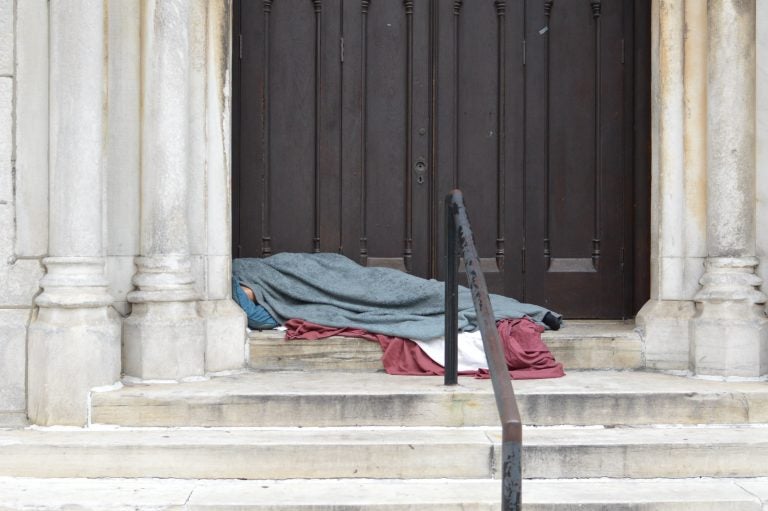 With only an elbow visible, a person experiencing homelessness sleeps in a door way at a Center City Church (Tom MacDonald, WHYY)