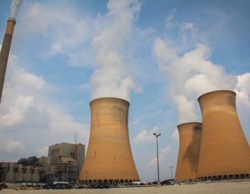 Cooling towers belch white smoke into the cloudy blue sky