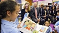 Comcast CEO Brian Roberts and his wife, Aileen (center), listen as Hackett School third-grader Madison Boudreaux reads. Through their foundation, the Robertses donated $450,000 to put books in Philadelphia public school classrooms. (Emma Lee/WHYY)