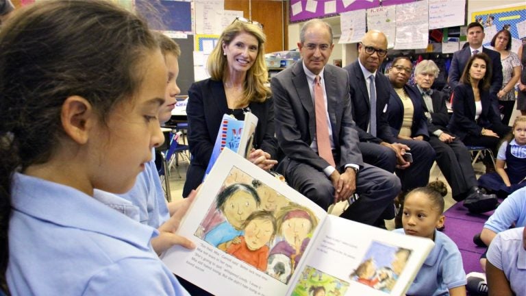 Comcast CEO Brian Roberts and his wife, Aileen (center), listen as Hackett School third-grader Madison Boudreaux reads. Through their foundation, the Robertses donated $450,000 to put books in Philadelphia public school classrooms. (Emma Lee/WHYY)