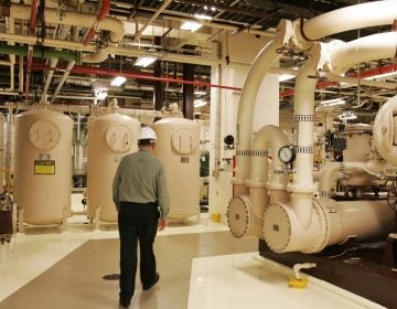 A man in a hard hat walks past equipment in the turbine building of a nuclear energy facility