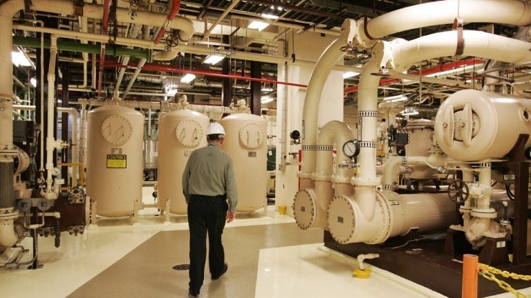 A man in a hard hat walks past equipment in the turbine building of a nuclear energy facility