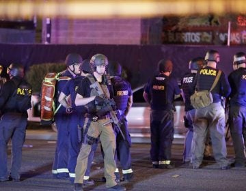 Police officers and medical personnel stand at the scene of a shooting near the Mandalay Bay resort and casino on the Las Vegas Strip